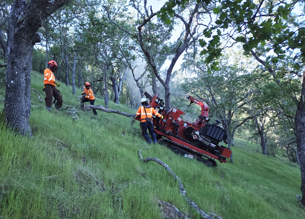 Tracked Chipper on sidehill being fed debris